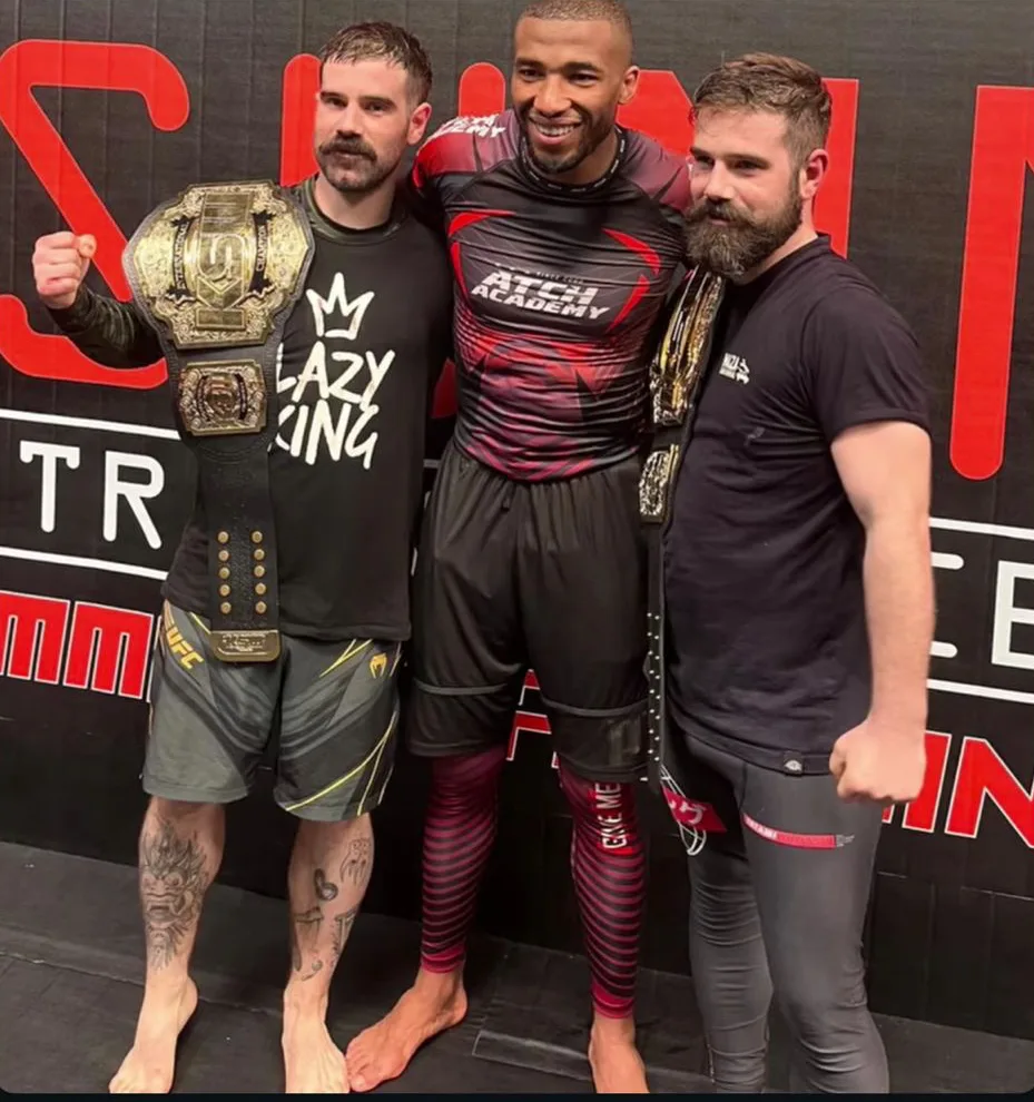 Photo souvenir partagée en story par le salon : trois passionnés de MMA, ceintures de champion en main